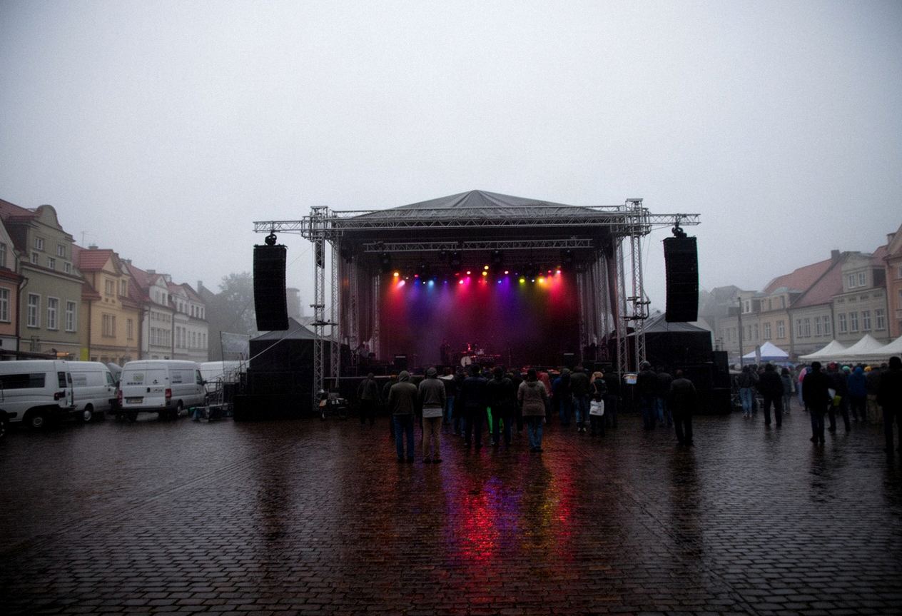 Scena plenerowa podczas wieczornego koncertu na miejskim placu, kolumny nagłośnienia i tłum z tyłu