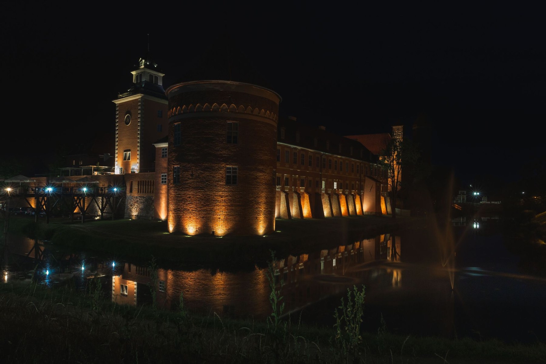 Oświetlony zamek w Lidzbarku Warmińskim odbijający się nocą w wodzie